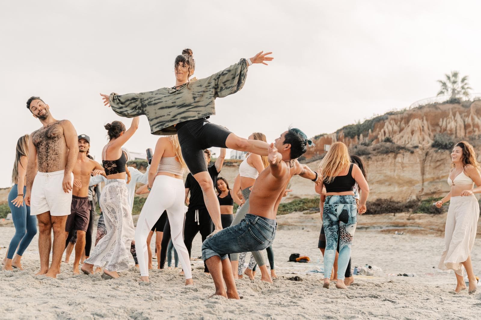 Friends lifting and catching one another in a burst of play on the beach