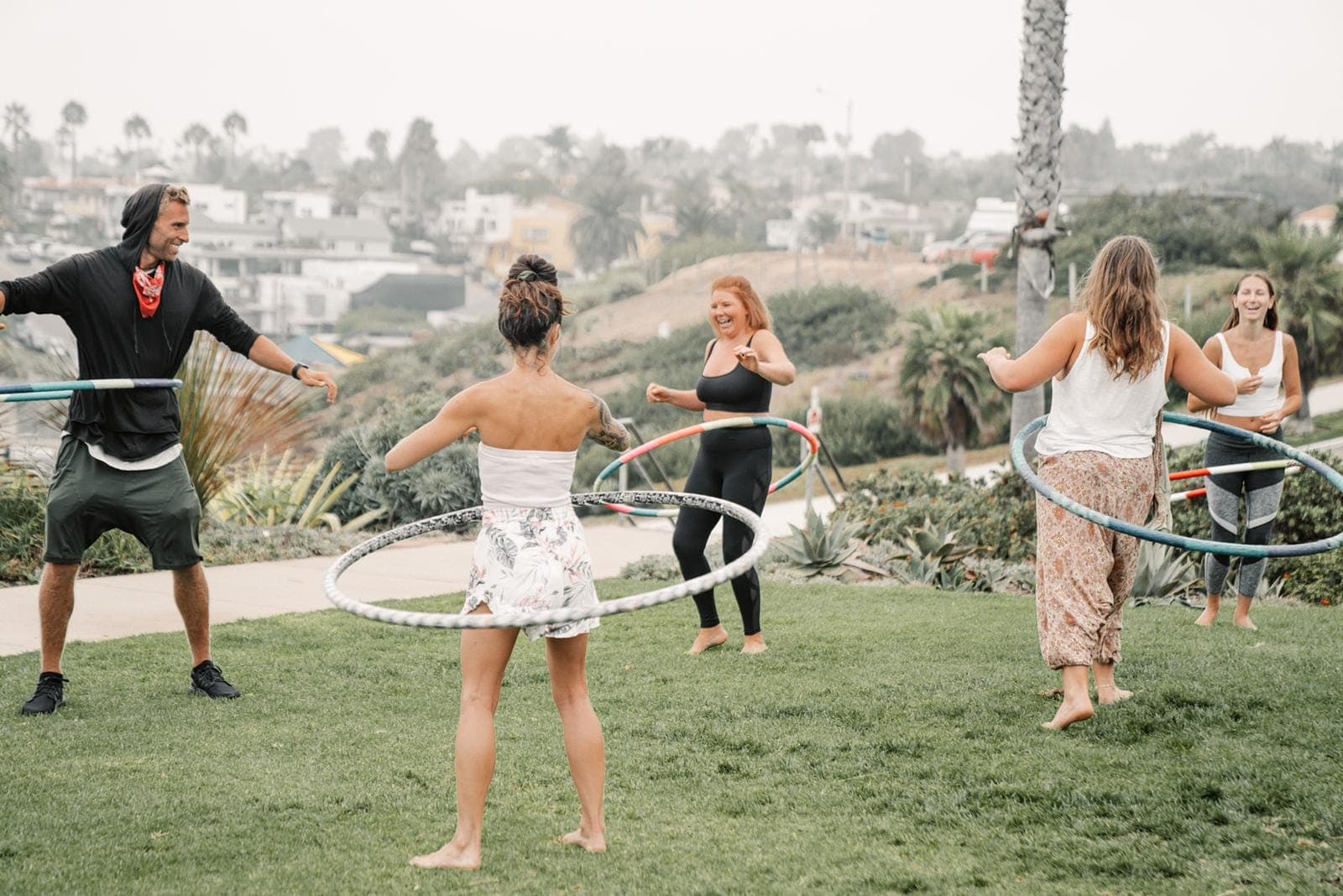 People playing with hula hoops together on a sunny lawn